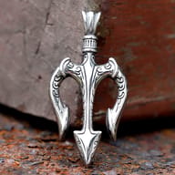 Close-up of ornate carved scrollwork and barbed prongs on stainless steel trident pendant