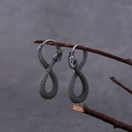 Detail of the twisted body and tail of the right stainless steel snake earring, with wood shavings.