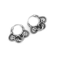 A pair of Men's 316L stainless steel snake hoop earrings displayed on a natural branch, emphasizing their robust construction and bold design.
