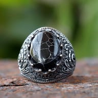 Detailed view of the intricate scrollwork design on the side of the stainless steel ring.