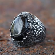 Profile view of the patterned stainless steel ring's band and setting of the black stone.
