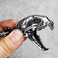 Close-up of the upper skull detail of the saber-toothed tiger pendant, with textured metal finish.