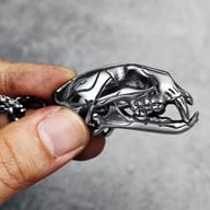 Extreme close-up of the lower jaw and eye socket area of the stainless steel saber-toothed tiger skull pendant.