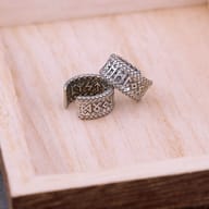 Close-up of the Elder Futhark rune engravings on an oxidized steel ear cuff