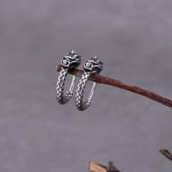 Close-up of sculpted dragon head and scale texture on the steel hoop earring