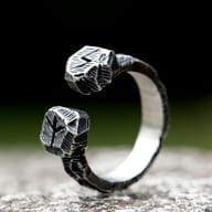 Close-up of engraved Norse rune terminals on textured stainless steel ring