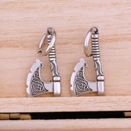 Pair of stainless steel Viking axe drop hoop earrings on a light wooden background