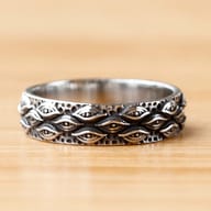 Detailed view of the carved eye pattern on the stainless steel ring's band