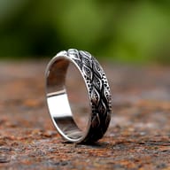 Side view of the stainless steel ring showing the textured carving and smooth band edge