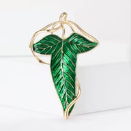 Green enamel elven leaf brooch pin with gold vine detailing on white background