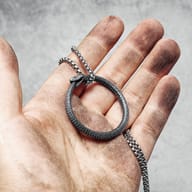 Close-up of Ouroboros snake pendant showing textured body and circular form