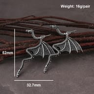 Gothic stainless steel dragon earrings displayed against rustic wooden accents
