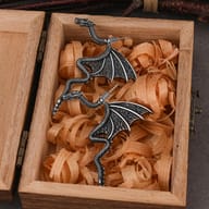 Close-up of the winged dragon earring showcasing intricate scale texture and antique finish