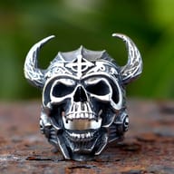 Close-up of a 316L stainless steel Viking warrior skull ring with horned helmet on a rustic surface