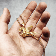 Close-up of the Pegasus pendant's winged horse design and gold-tone chain.