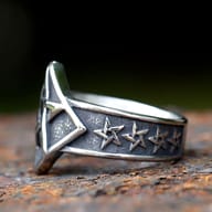 Detailed view of the pentagram ring's central design on a rustic surface.