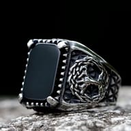 Stainless steel ring with an antique finish, featuring a rectangular black stone centerpiece and an intricately carved Yggdrasil design on the side.