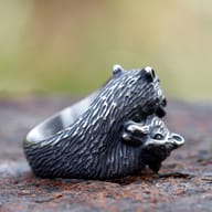 Close-up emphasizing the textured tail and body of the fox ring, on a rusted surface.