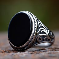 Close-up of men's retro silver ring with prominent oval black stone and intricate band carving