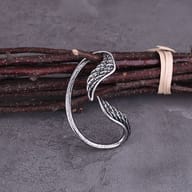 Both stainless steel wing earrings displayed against rustic wood shavings