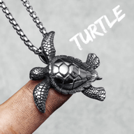 Detailed 316L stainless steel turtle pendant necklace on a finger, showcasing its textured shell and flippers.