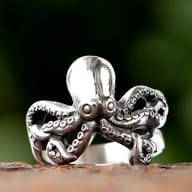 A shiny stainless steel ring featuring a detailed octopus design with oxidized tentacles and visible suckers.