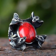 Detailed view of the upper left snake head and part of the red zircon on a 316L stainless steel ring.