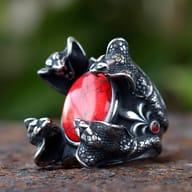 Three-quarter view of the 316L stainless steel ring, emphasizing the powerful design of four snake heads cradling a red zircon.