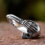 Angled view of the stainless steel skull ring, showing the texture and finish of the metal.
